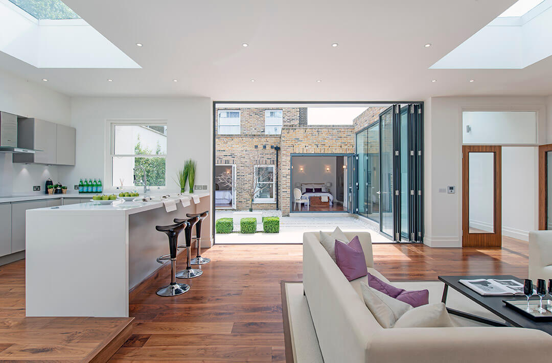 Open-plan kitchen extension with skylights and bi-fold doors by UrbanWorks